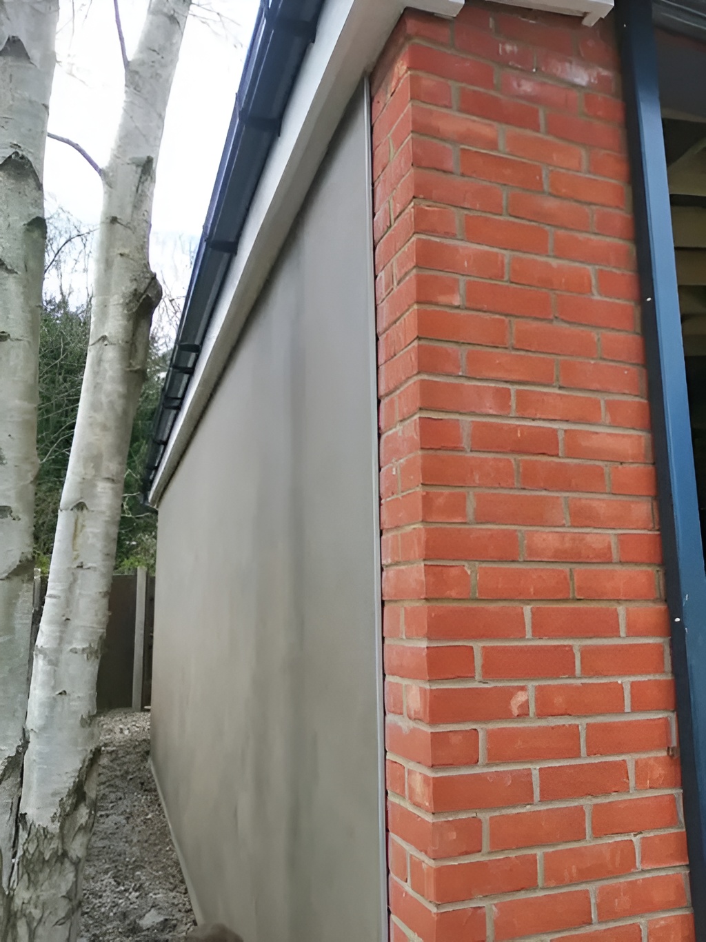 Smooth silicone render alongside red brickwork